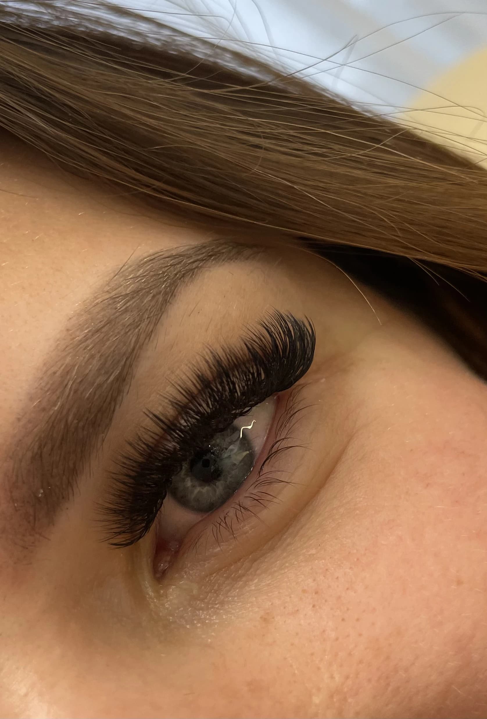 Blue-eyed client with dense 4D volume lash extensions and a softly groomed light brow at My Beauty Space.