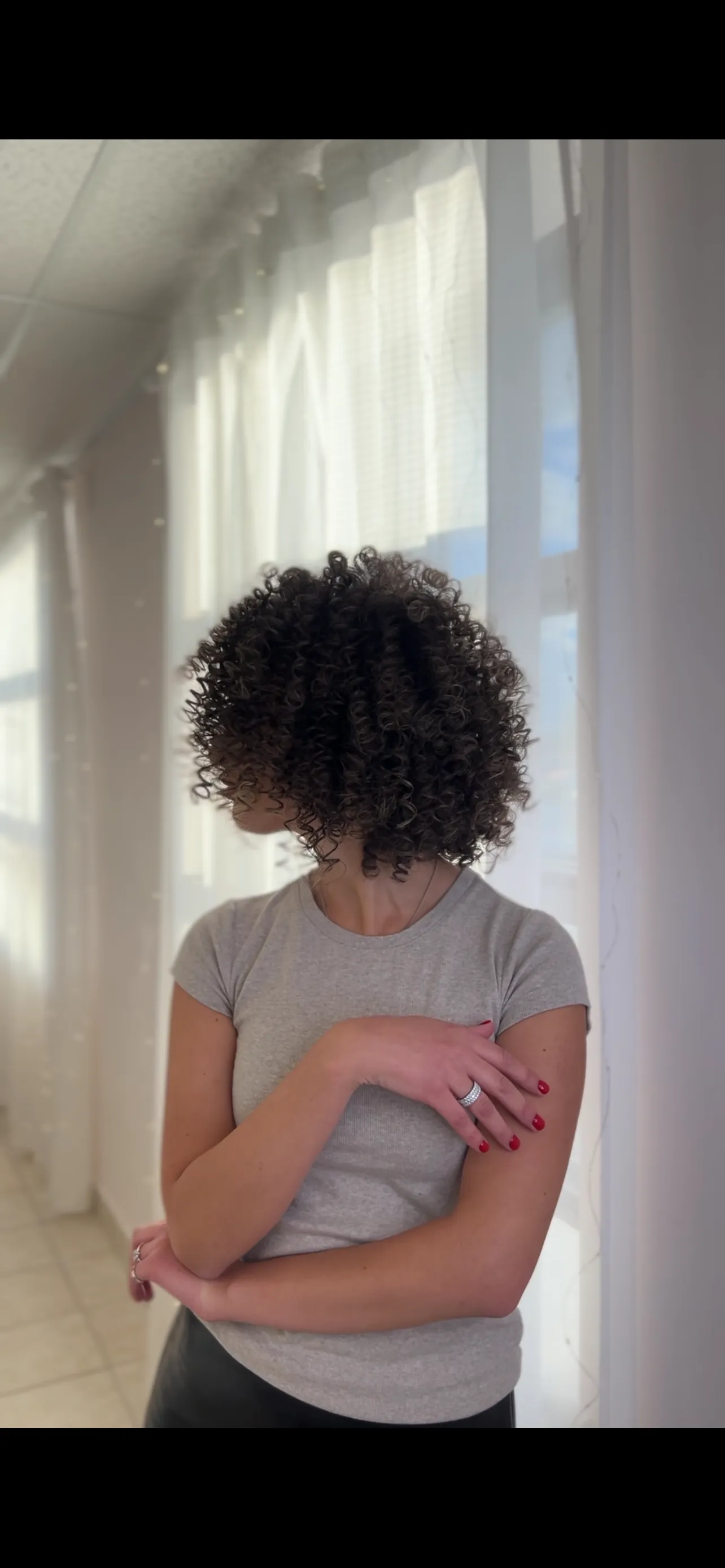 Voluminous dark-brown ringlet curls shown from the side in soft salon window light at My Beauty Space Mississauga.