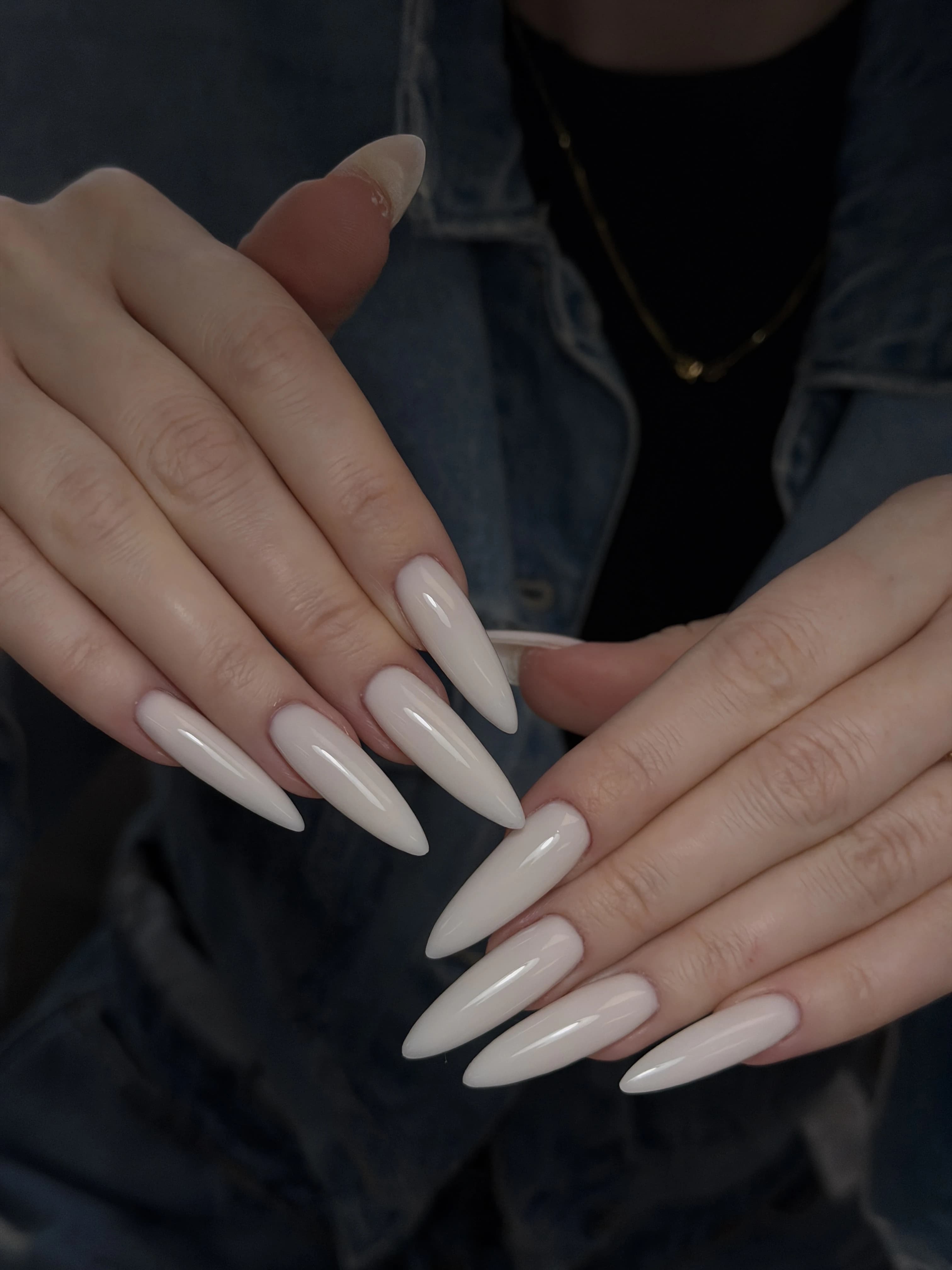 Extra-long stiletto Gel-X at My Beauty Space in pearly off-white high gloss, hands layered over a denim jacket.