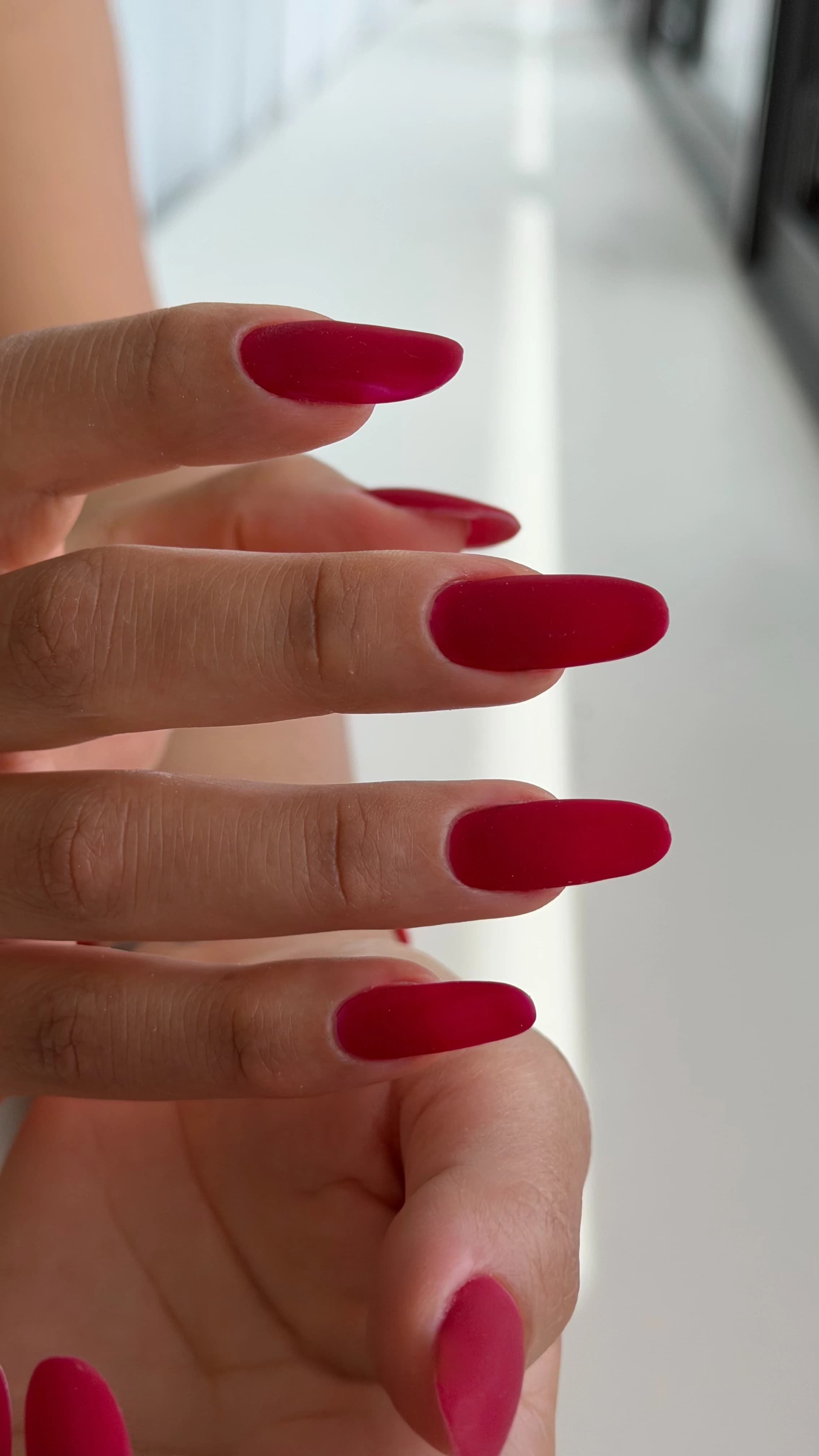 Mississauga Gel-X extensions in long oval shapes coated with velvety matte raspberry-red jelly polish.