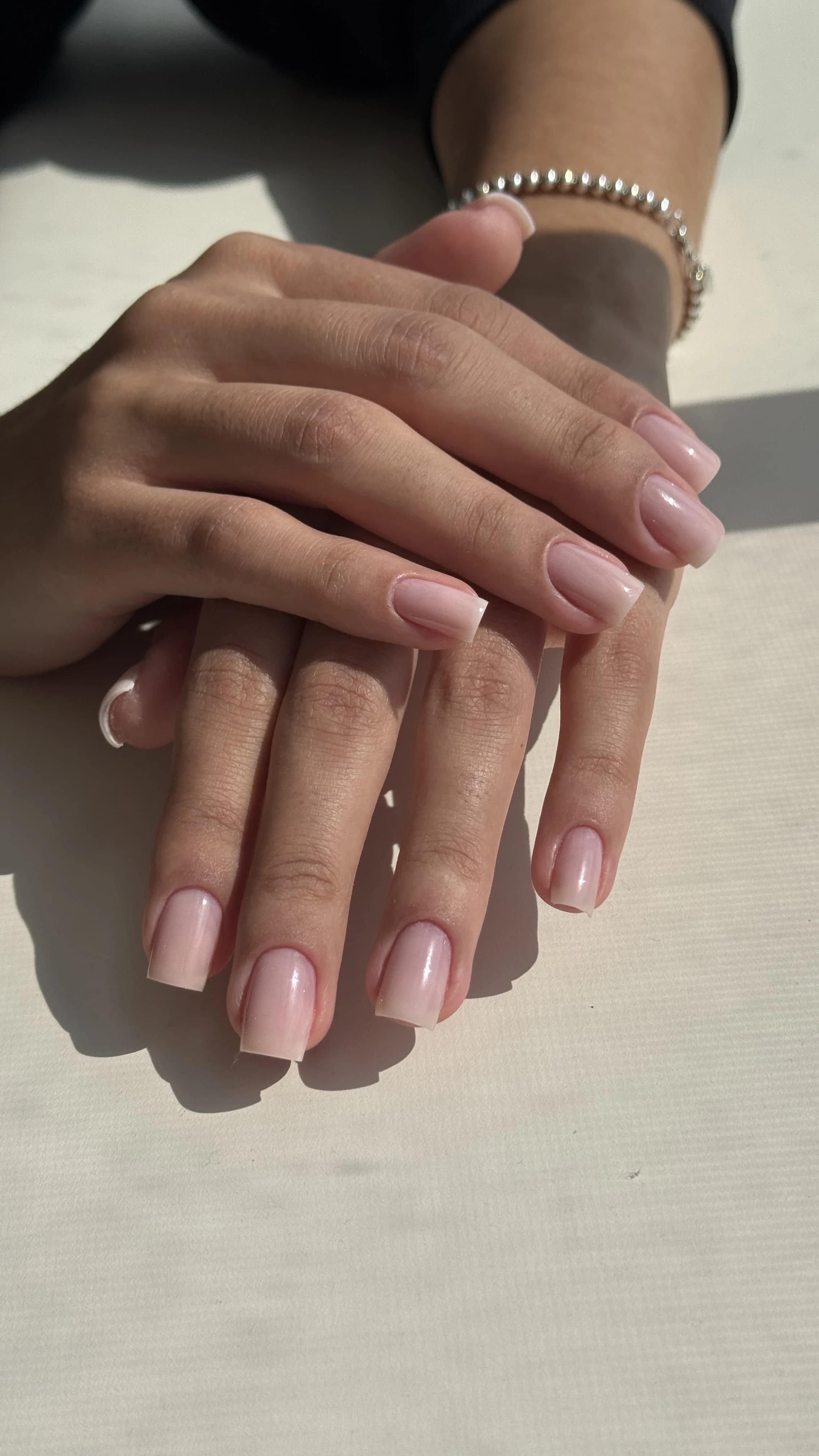Translucent milky-pink gel polish on square nails with a beaded silver bracelet, finished at My Beauty Space in Mississauga.